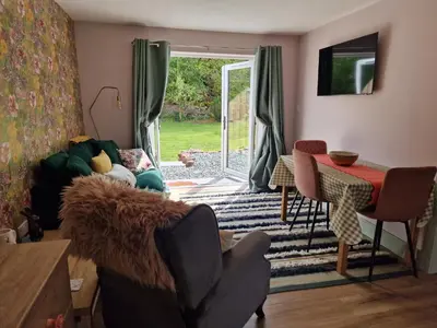 a living room with a table and chairs and a sliding glass door at The Burrow by Blake View Holidays a peaceful boutique retreat 3 miles from Ennerdale- standard twin or super-king bed available in Rowrah