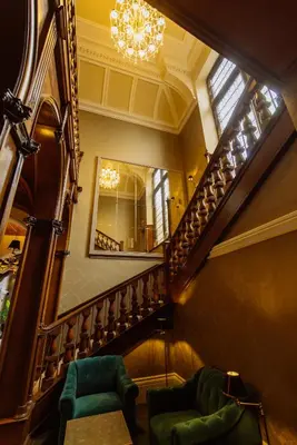 a staircase with two green chairs and a mirror at Cornhill Castle in Biggar