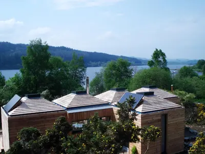 a row of houses with a lake in the background at Red Kite Eco Bothy - with Hot Tub in Castle Douglas