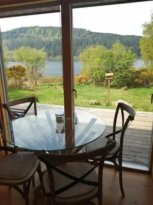 a glass table and chairs in front of a window at Red Kite Eco Bothy - with Hot Tub in Castle Douglas