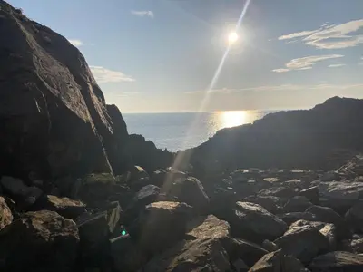a sun setting over the ocean on a rocky beach at Cosy Holiday Home Portpatrick in Portpatrick