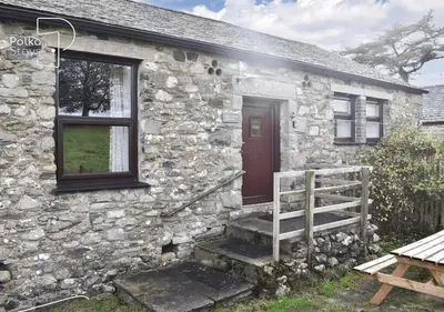 a stone house with a red door and a wooden porch at The Stables Lake District Retreat by PolkaStays in Troutbeck