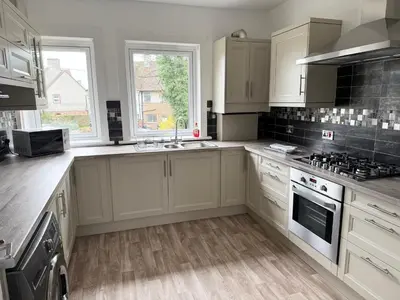 a kitchen with white cabinets and a stove top oven at Modern 2 bed with secure driveway in Dumfries