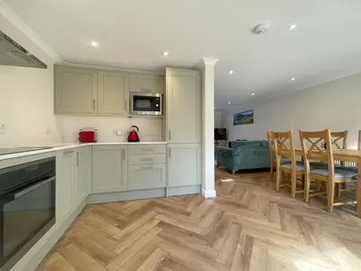 a kitchen with white cabinets and a dining room at Farmers Retreat in Keswick