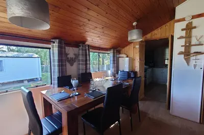 a dining room with a wooden table and chairs at Wildwood Cabin - Sleeps 6 Hot Tub & Parking in Beattock