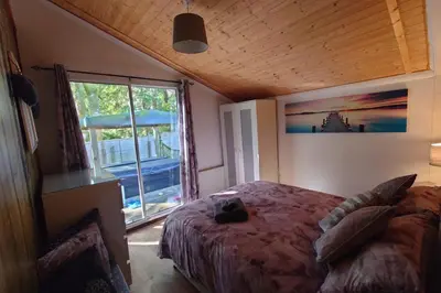 a bedroom with a bed and a large window at Wildwood Cabin - Sleeps 6 Hot Tub & Parking in Beattock