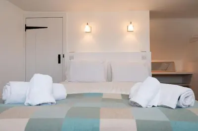 a bedroom with a bed with white blankets and pillows at Cross Cottage in Gatehouse of Fleet