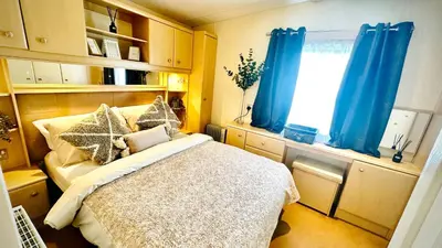 a bedroom with a bed with blue curtains and a window at Shoreline Stay in Port Carlisle