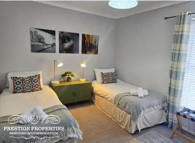 a bedroom with two beds and a desk and a window at Harcourt by Prestige Properties SA in Workington