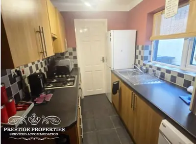 a kitchen with a black counter top and a white refrigerator at Harcourt by Prestige Properties SA in Workington