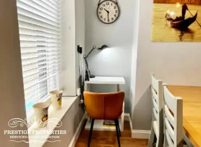 a desk and a chair in a room with a clock at Harcourt by Prestige Properties SA in Workington