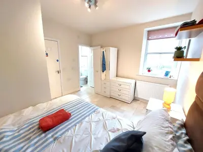 a bedroom with a bed with a red pillow on it at Ensuite rooms, self-catering in shared kitchens in Dumfries