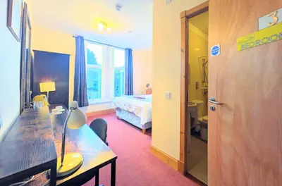 a room with a table and a bed and a bedroom at Ensuite rooms, self-catering in shared kitchens in Dumfries