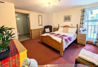a bedroom with a bed and a chair in it at Ensuite rooms, self-catering in shared kitchens in Dumfries