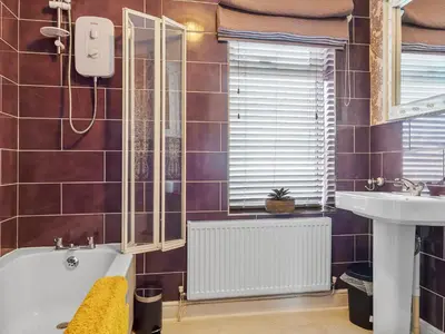 a bathroom with a sink and a bath tub and a mirror at Workington Haven - 3 Bed Home in Workington