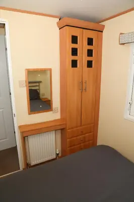 a bedroom with a mirror and a wooden cabinet at Shelly's Stay in Port Carlisle