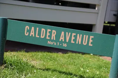 a green sign for calder avenue sitting in the grass at Shelly's Stay in Port Carlisle