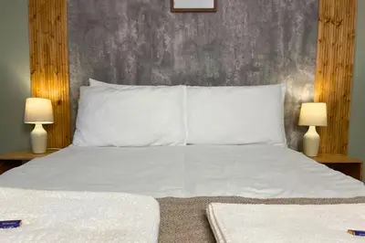 a bedroom with a white bed with two lamps at Secluded Hot Tub, Pool, Escape in Bootle