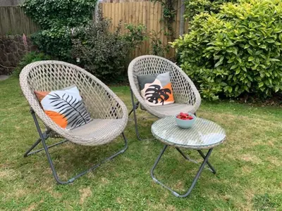two wicker chairs and a table in a yard at The Gower Cottages in Moffat