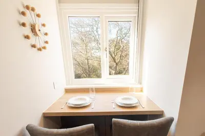 a wooden table with two plates and a window at Stoneyloft Modern Apartment in Glen Vine in Glen Vine