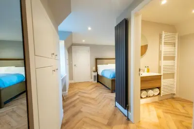 a bedroom with a bed and a bathroom with a sink at Stoneyloft Modern Apartment in Glen Vine in Glen Vine