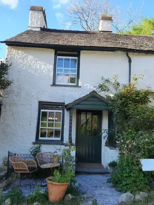 a white house with a black door and chairs at Blea Tarn Farmhouse B&B in Ambleside