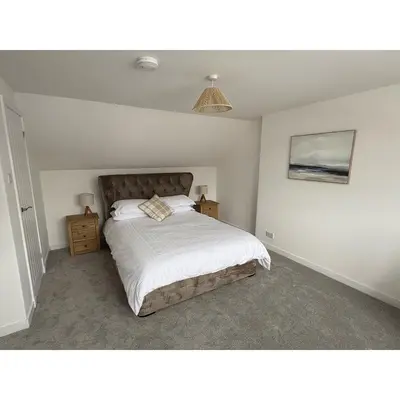 a bedroom with a large bed with white sheets at Modern 3-Bedroom, central Kirkcudbright in Kirkcudbright