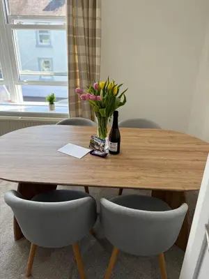 a wooden table with a vase of flowers and two chairs at Modern 3-Bedroom, central Kirkcudbright in Kirkcudbright