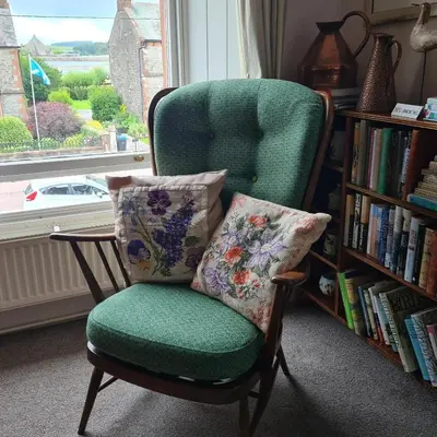 a green chair with a pillow and a book shelf at 95 St Mary Street in Kirkcudbright