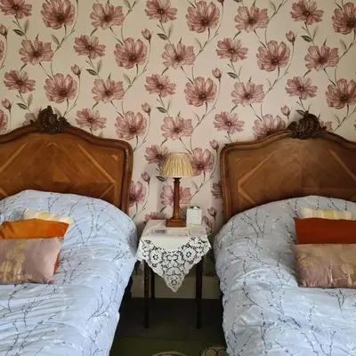 two beds in a bedroom with flowers on the wall at 95 St Mary Street in Kirkcudbright