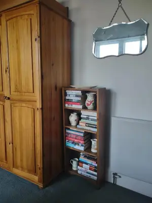 a book shelf filled with books next to a cabinet at 95 St Mary Street in Kirkcudbright