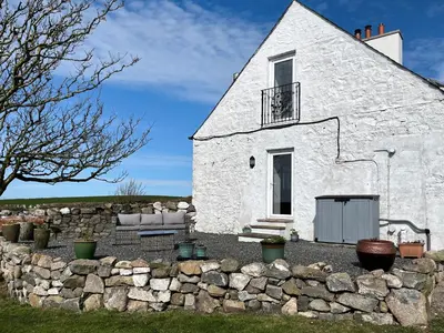 a white building with a stone wall in front of it at The Cheese Loft in Drummore