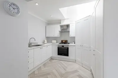 a kitchen with white cabinets and a clock on the wall at Stunning 2 bedroom Apartment in Central Keswick in Keswick