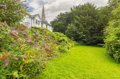a garden with purple flowers and a white house at Stunning 2 bedroom Apartment in Central Keswick in Keswick