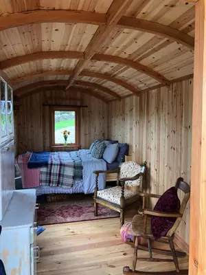 a bedroom with a bed and a chair in a room at Barmoffity Shepherds Hut in Kirkpatrick Durham