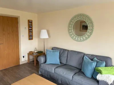 a living room with a gray couch and a mirror at Pottery Cottage - close to the Lake District in Skelton