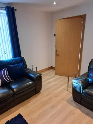 a living room with a leather couch and a door at 2 Hares Den in Annan
