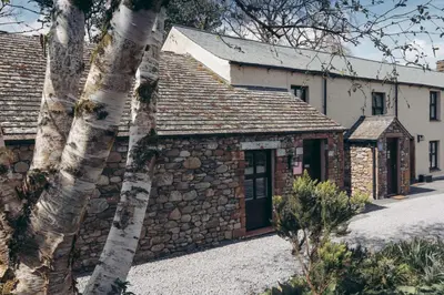 an old stone building with a stone wall at North Lakes - The Fold Holiday Cottage in Penrith