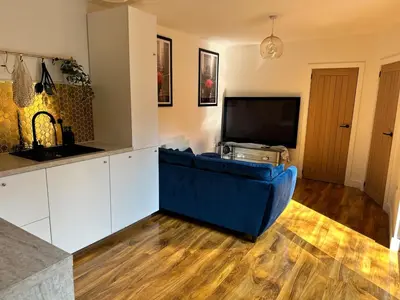 a living room with a blue couch and a tv at Scotney Retreat in Moffat