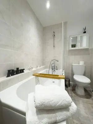 a white bathroom with a tub and a toilet at Spacious 4-Bed Lake District Getaway for Groups in Mealsgate
