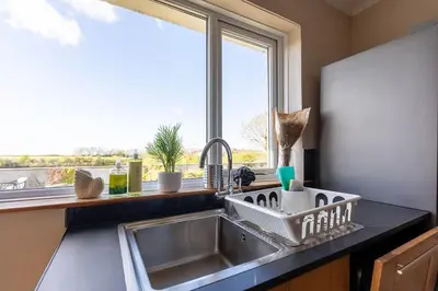 a kitchen sink with a dish drying rack next to a window at Spacious 4-Bed Lake District Getaway for Groups in Mealsgate