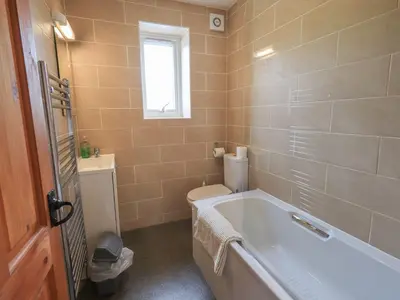 a bathroom with a tub and a toilet and a window at Capella Cottage in Keswick