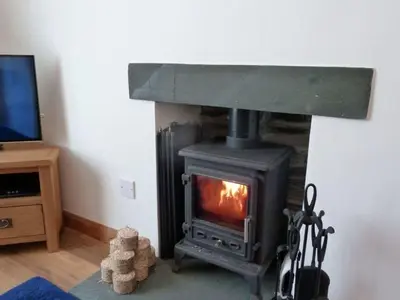 a fireplace in a living room with a stove at Capella Cottage in Keswick