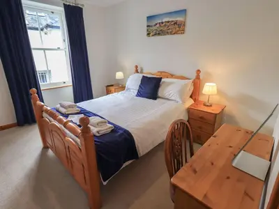 a bedroom with a wooden bed and a table at Capella Cottage in Keswick
