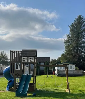 a playground with a slide and a play structure at Creebridge Caravan Park in Newton Stewart