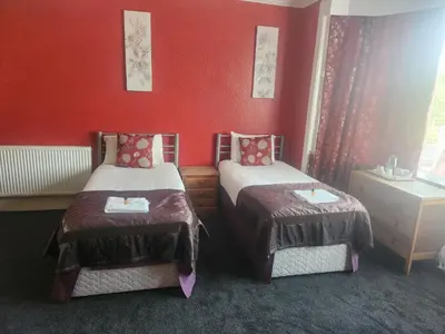 two beds in a room with red walls at LSO Guest House in Dumfries