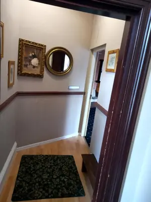 a hallway in a house with a mirror and a rug at LSO Guest House in Dumfries
