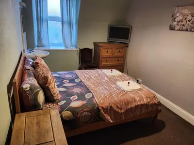 a small bedroom with a bed and a sink at LSO Guest House in Dumfries