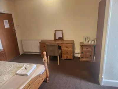 a bedroom with a dresser and a desk with a mirror at LSO Guest House in Dumfries