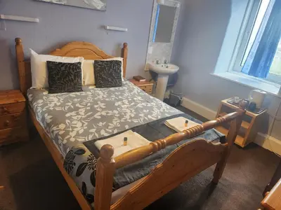 a bedroom with a wooden bed and a sink at LSO Guest House in Dumfries